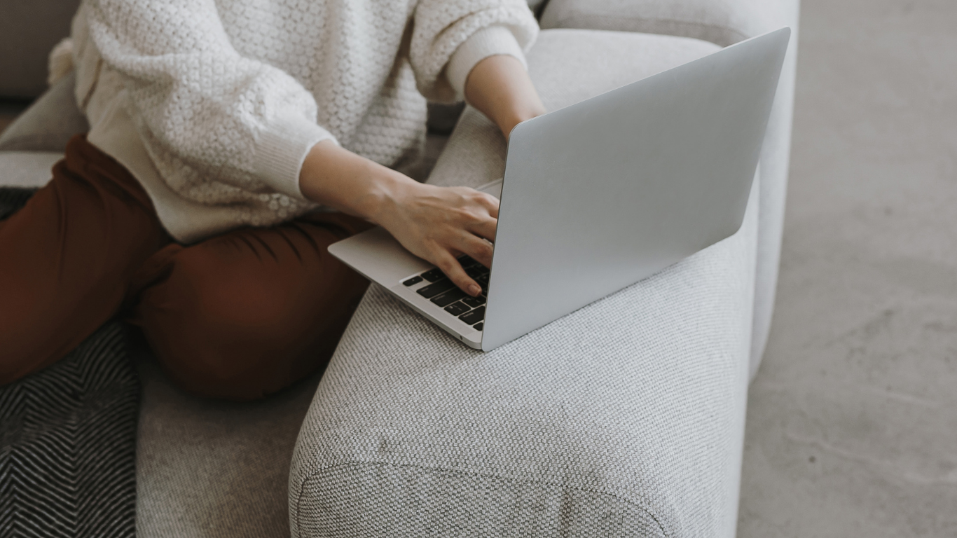Working on a laptop while seated on a light fabric sofa